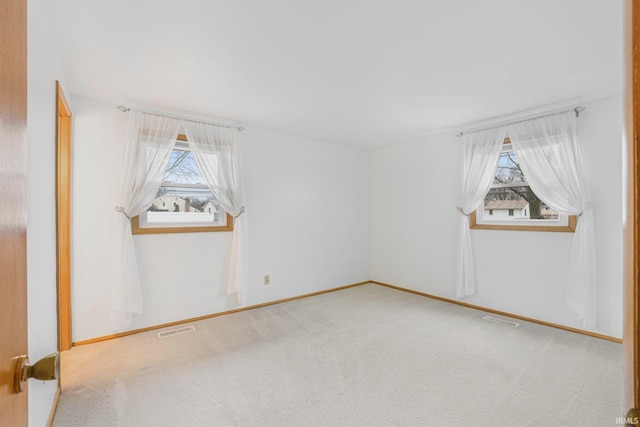 carpeted empty room featuring plenty of natural light and visible vents