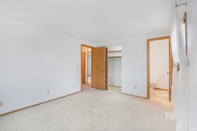 unfurnished bedroom featuring a closet, light colored carpet, visible vents, connected bathroom, and baseboards