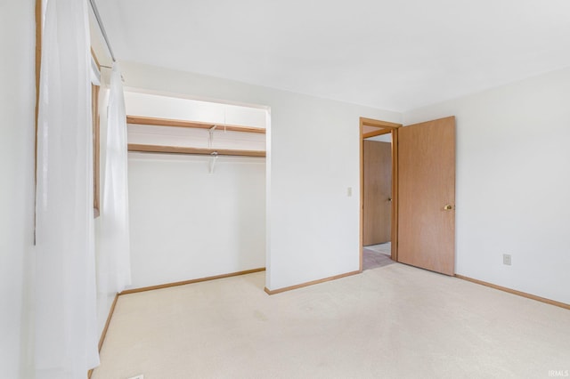 unfurnished bedroom with baseboards, a closet, and light colored carpet