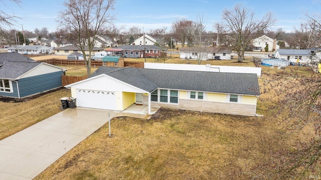 view of front of property featuring a garage, a shingled roof, fence, driveway, and a residential view