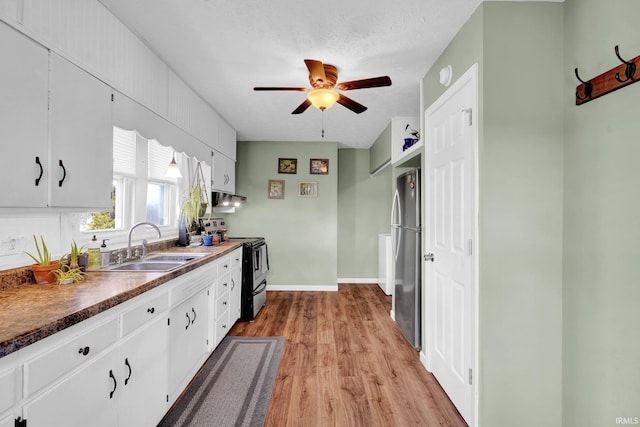 kitchen with range with electric cooktop, freestanding refrigerator, white cabinets, and a sink