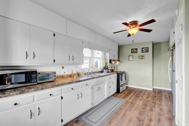 kitchen with a toaster, appliances with stainless steel finishes, white cabinets, a sink, and light wood-type flooring