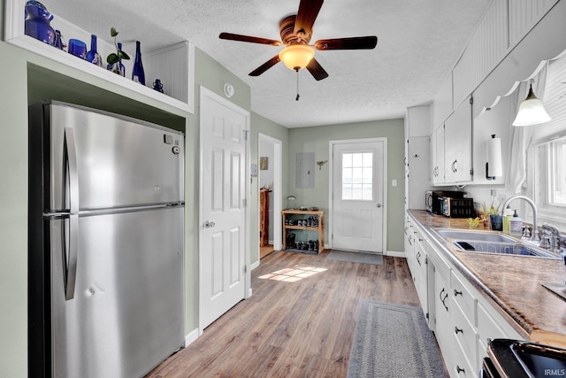 kitchen featuring light wood finished floors, open shelves, appliances with stainless steel finishes, white cabinetry, and a sink