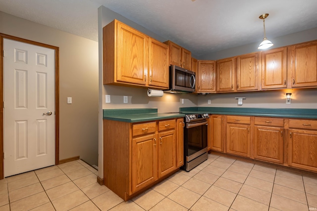 kitchen with light tile patterned floors, stainless steel appliances, brown cabinets, and a textured ceiling