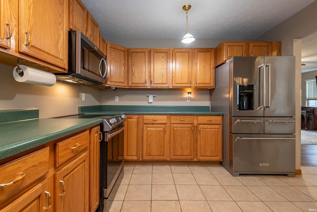 kitchen featuring dark countertops, appliances with stainless steel finishes, light tile patterned flooring, and brown cabinetry