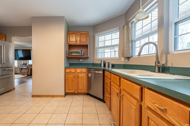 kitchen featuring pendant lighting, a sink, dark countertops, stainless steel appliances, and light tile patterned floors