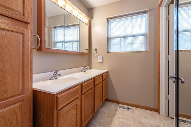 bathroom with a sink, visible vents, baseboards, and double vanity