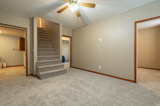 interior space featuring stairway, a ceiling fan, baseboards, and light carpet