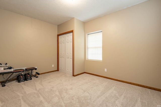 bedroom with a closet, baseboards, a textured ceiling, and carpet flooring