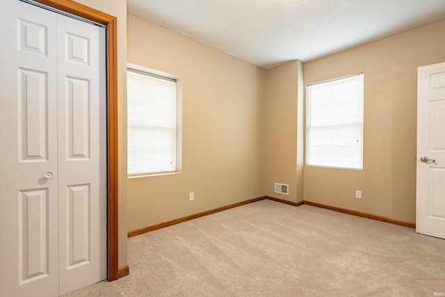 unfurnished bedroom with light carpet, visible vents, and baseboards