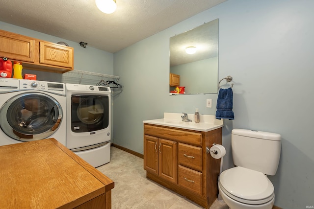 laundry room featuring baseboards, laundry area, a sink, a textured ceiling, and independent washer and dryer