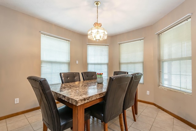 dining space with a notable chandelier, light tile patterned floors, and baseboards