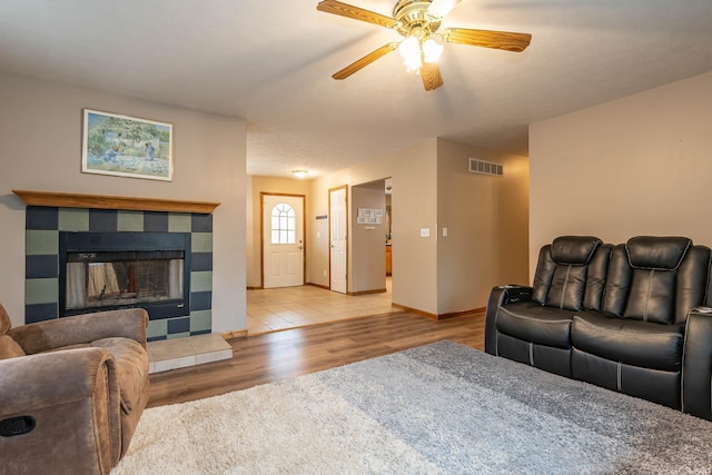 living area featuring visible vents, baseboards, a fireplace, wood finished floors, and a ceiling fan