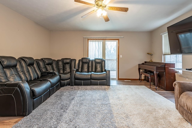 living area with baseboards, wood finished floors, and a ceiling fan