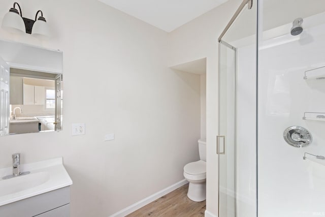 full bath with toilet, a stall shower, vanity, wood finished floors, and baseboards