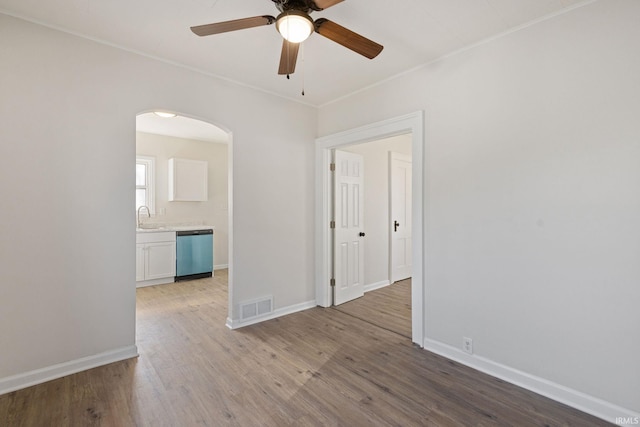 unfurnished room with arched walkways, baseboards, visible vents, and light wood-style floors