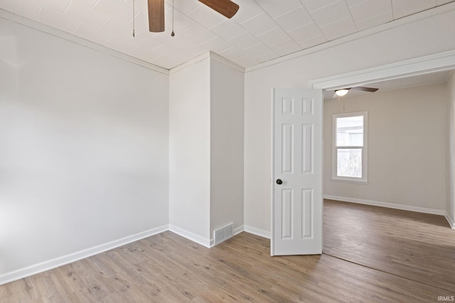 unfurnished room with a ceiling fan, visible vents, baseboards, and wood finished floors