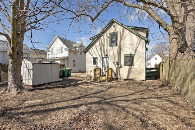 rear view of house with fence, an outdoor structure, and a shed