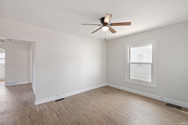 unfurnished room with light wood-style floors, ceiling fan, visible vents, and baseboards