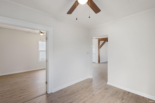 spare room with baseboards, ceiling fan, light wood-style flooring, and crown molding