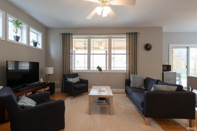 living room featuring light wood-style floors, ceiling fan, and baseboards