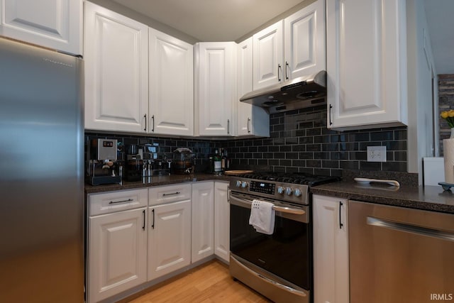 kitchen with appliances with stainless steel finishes, white cabinetry, under cabinet range hood, and decorative backsplash