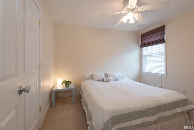 bedroom with light carpet, a ceiling fan, and baseboards