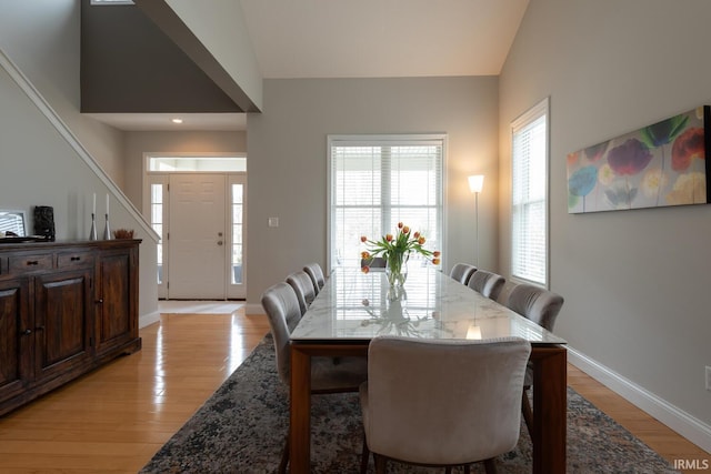 dining room with vaulted ceiling, light wood-style flooring, and baseboards