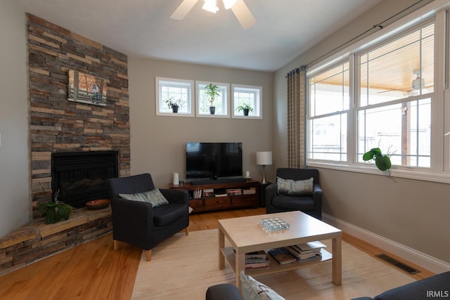 living area with baseboards, visible vents, ceiling fan, wood finished floors, and a fireplace