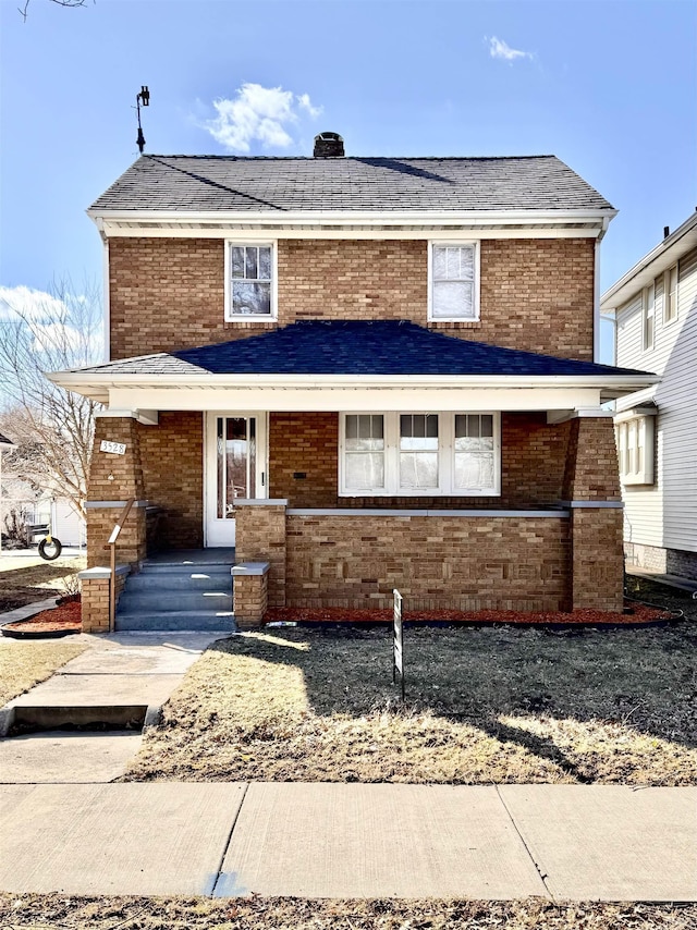 traditional-style home featuring brick siding, roof with shingles, and a porch