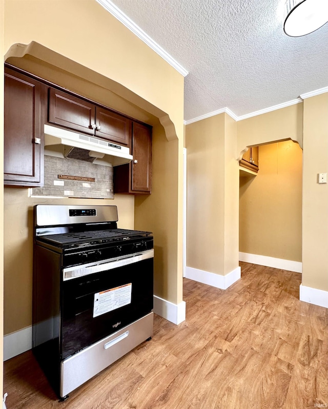 kitchen featuring under cabinet range hood, light wood-style flooring, stainless steel range with gas cooktop, and ornamental molding