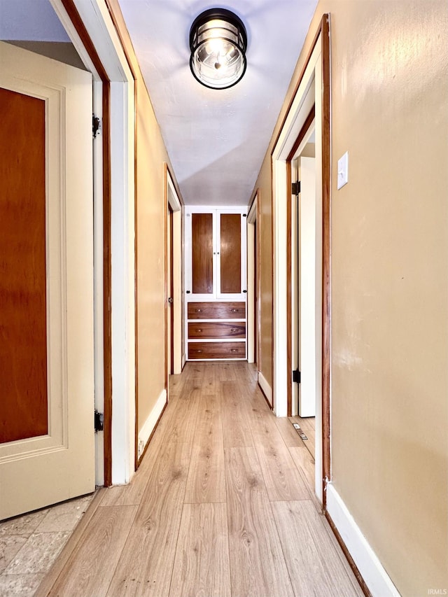 hall with light wood-style flooring and baseboards