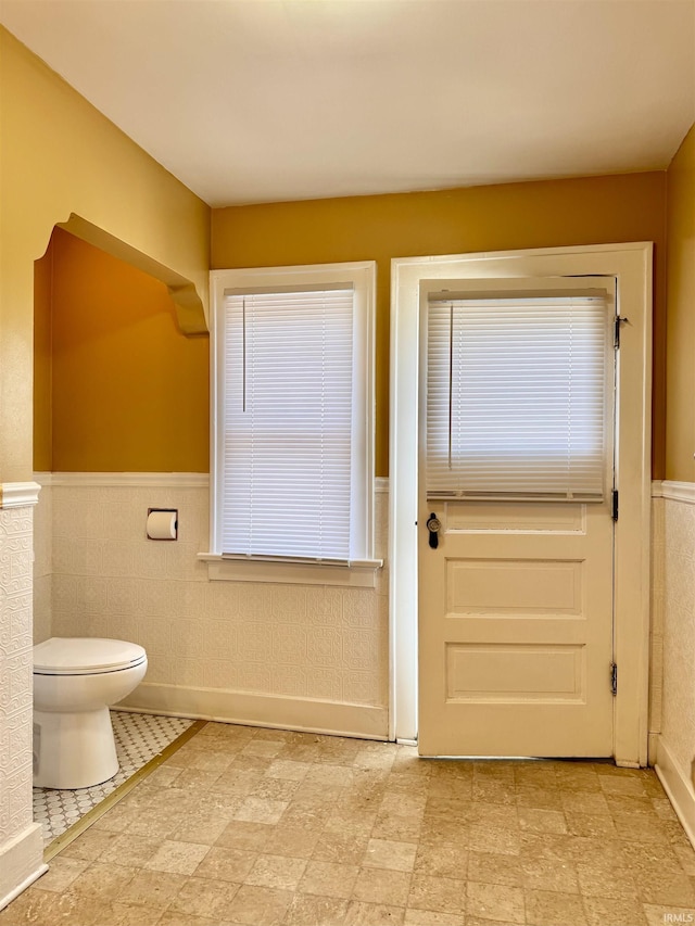 bathroom with toilet and a wainscoted wall