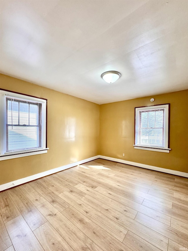 spare room with baseboards and wood finished floors