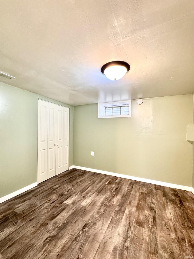 basement featuring visible vents, a textured ceiling, baseboards, and wood finished floors