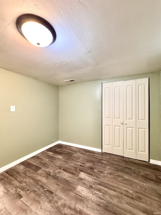 below grade area with visible vents, baseboards, and dark wood-type flooring