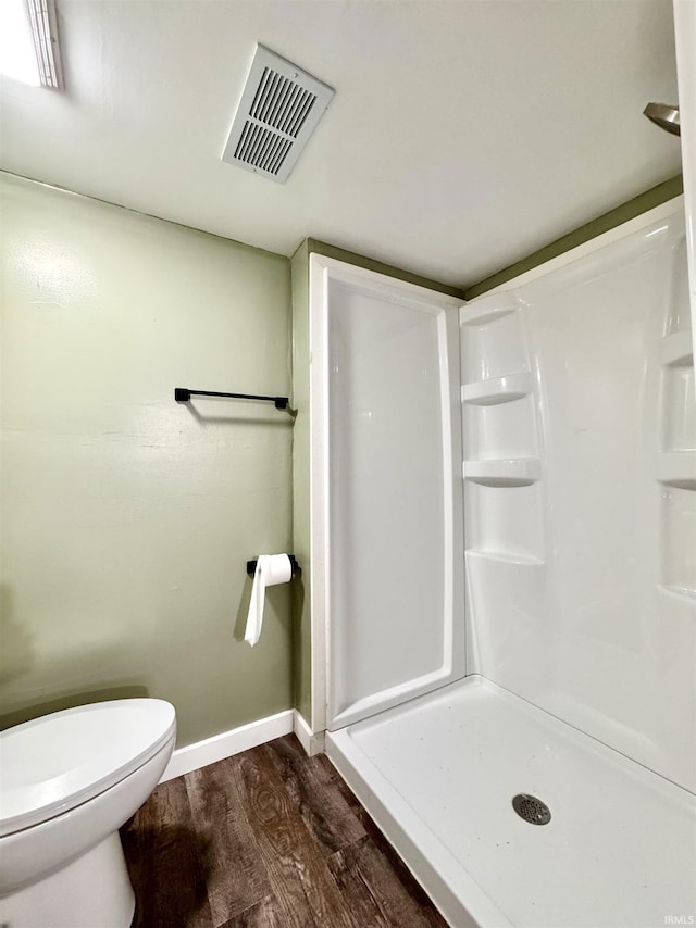 full bath with visible vents, toilet, a stall shower, wood finished floors, and baseboards