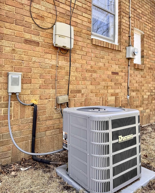 exterior details featuring brick siding, electric meter, and central air condition unit