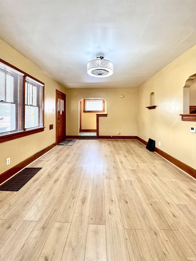 empty room featuring wood finished floors, visible vents, and baseboards