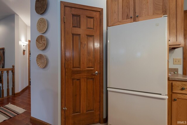 kitchen with wood finished floors, freestanding refrigerator, and brown cabinets