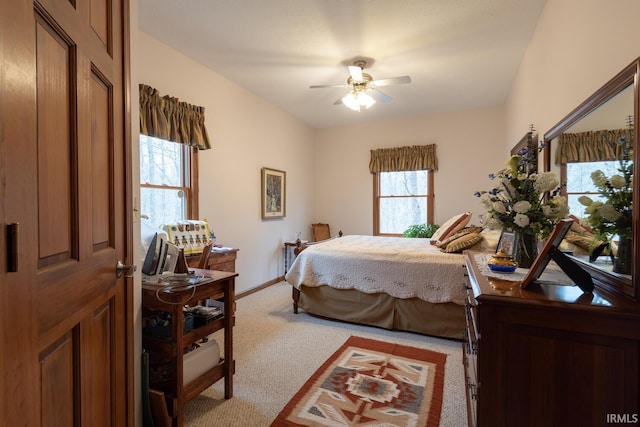 bedroom featuring a ceiling fan, light colored carpet, and baseboards