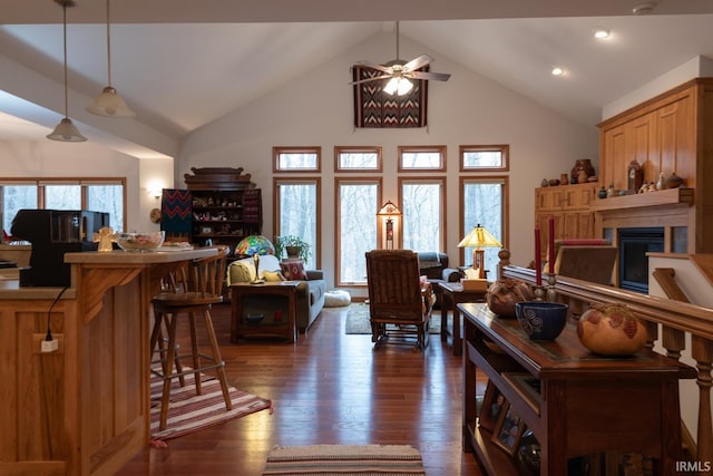 living room with high vaulted ceiling, a glass covered fireplace, dark wood finished floors, and ceiling fan