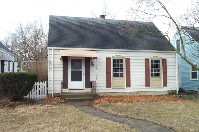 cape cod house featuring a shingled roof, a chimney, a front yard, and fence