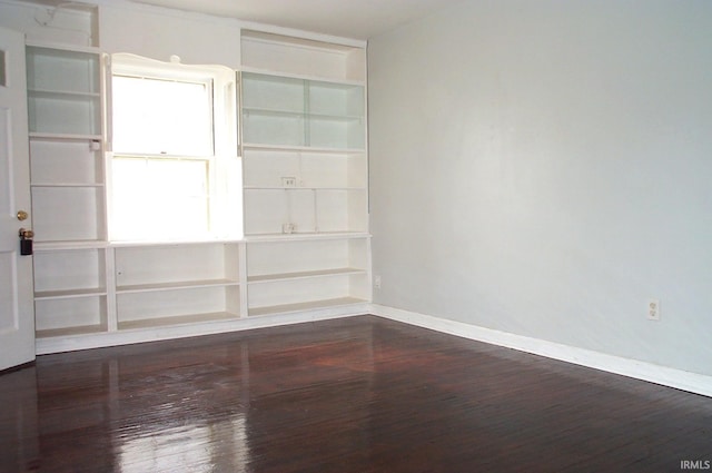 unfurnished room with dark wood-type flooring and baseboards