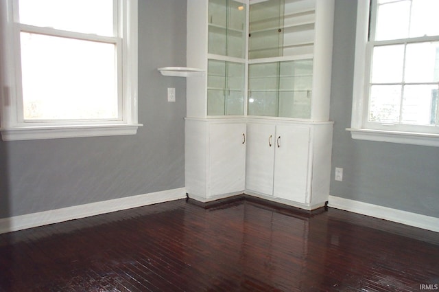 unfurnished room featuring baseboards and dark wood finished floors