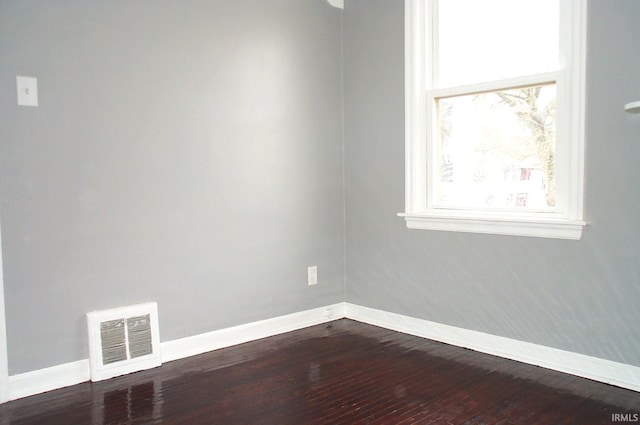 unfurnished room featuring visible vents, dark wood finished floors, and baseboards