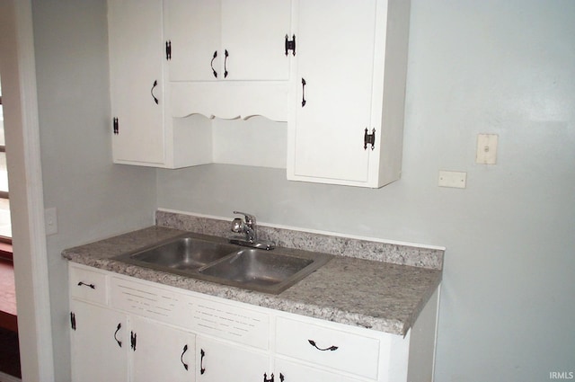 kitchen with light countertops, a sink, and white cabinets