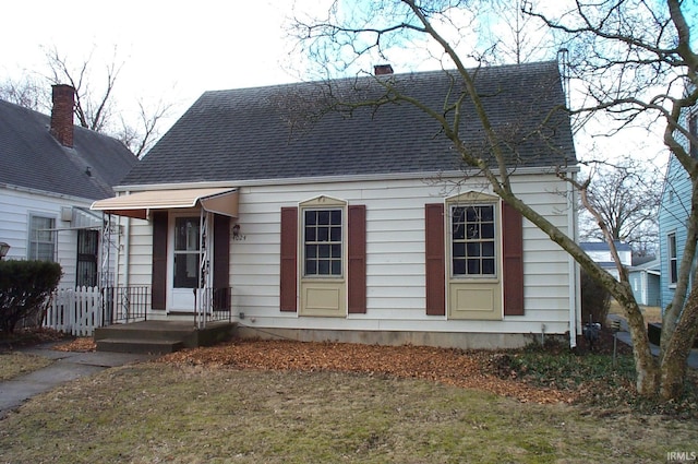 new england style home featuring roof with shingles and a chimney