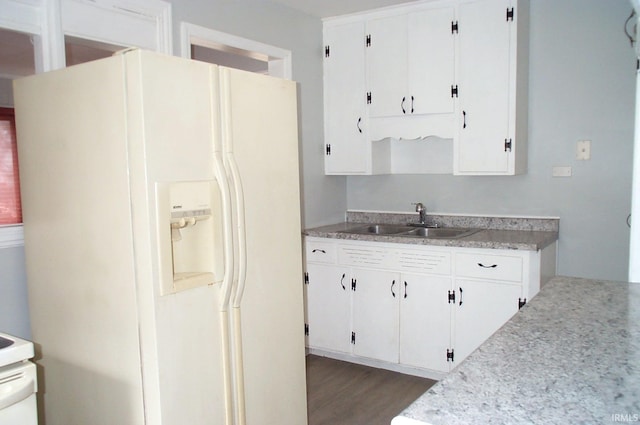 kitchen featuring white refrigerator with ice dispenser, white cabinetry, light countertops, and a sink