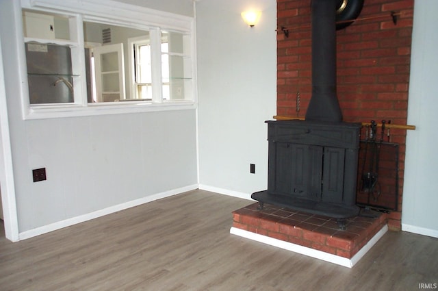 interior details featuring a wood stove, baseboards, wood finished floors, and refrigerator